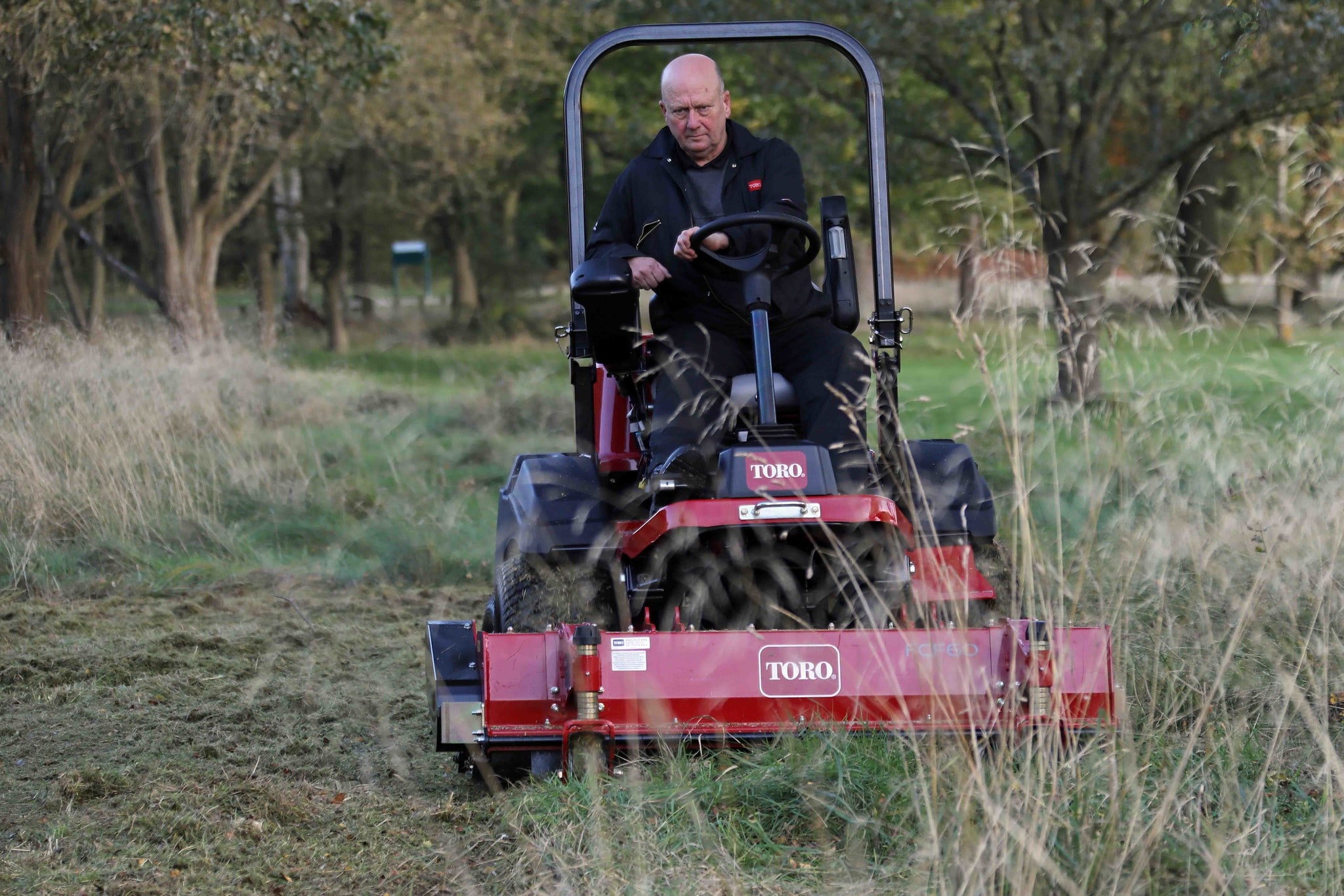 A Toro rotary mower cutting through the rough, longer grass.