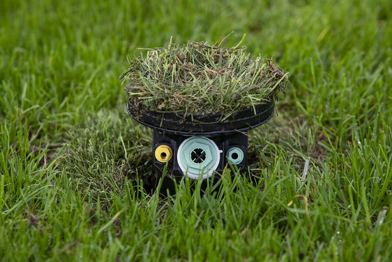 A close up of a Toro Irrigation sprinkler head above the ground.