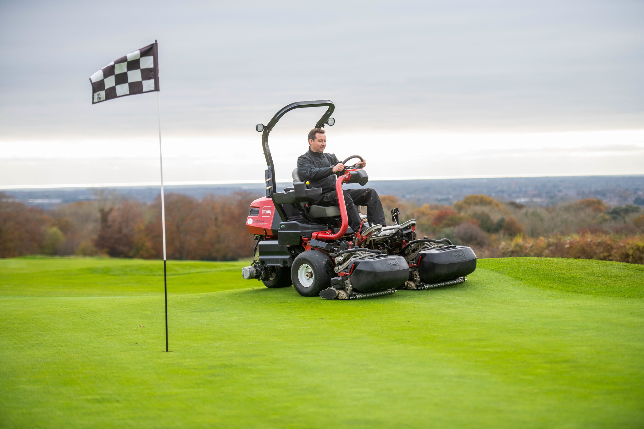 A greenkeeper riding a Toro eTriFlex 3370 on a green.